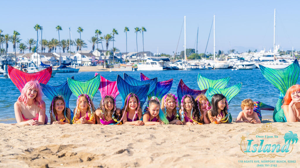 Mermaid Academy graduates in their tails on the beach in Newport Harbor