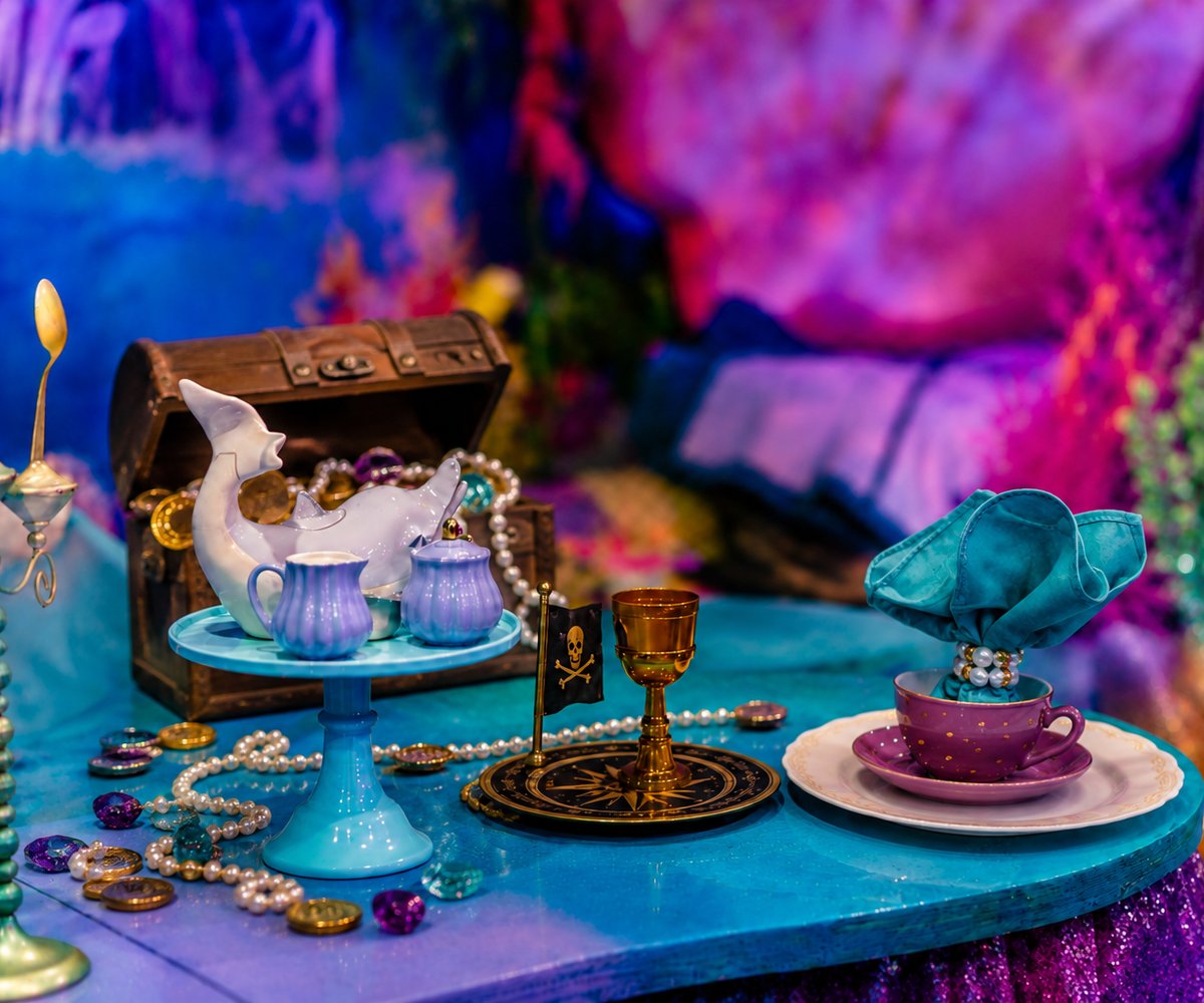 A treasure chest, gold coins, a skull flag and purple teacups on the table at a Neverland Adventure Party