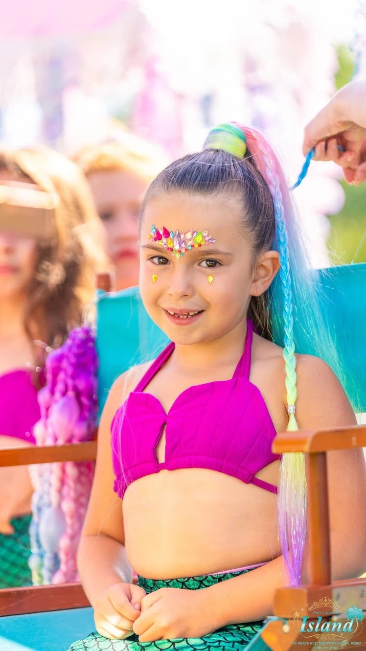 A mermaid makeover with colorful braids and face gems at Mermaid Cove