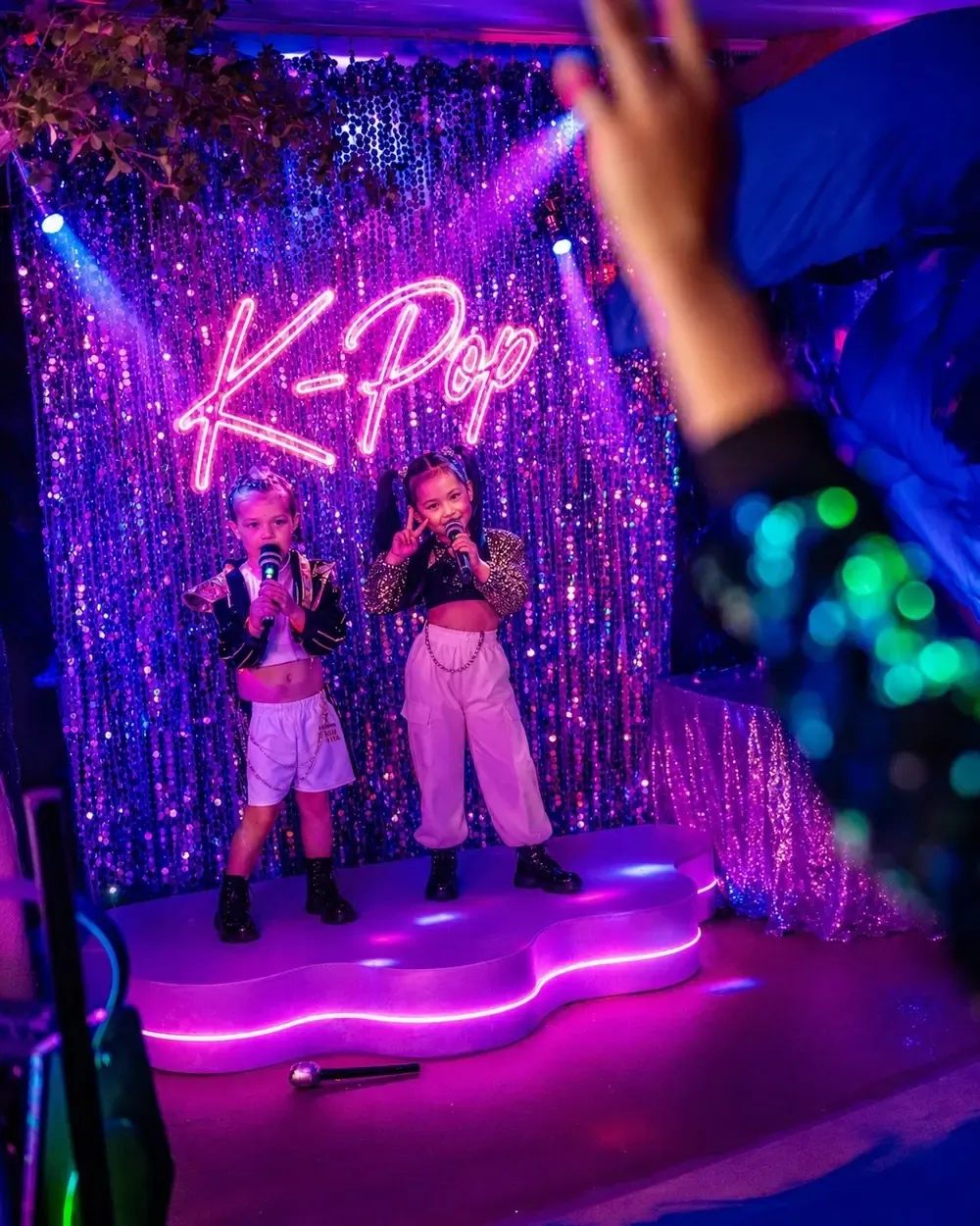 Two friends performing under the K-Pop neon