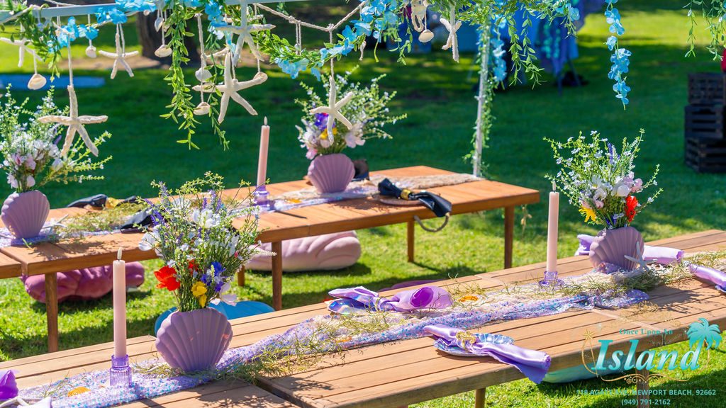Shell plates, starfish and a wildflower runner on the table at a mermaid travel party
