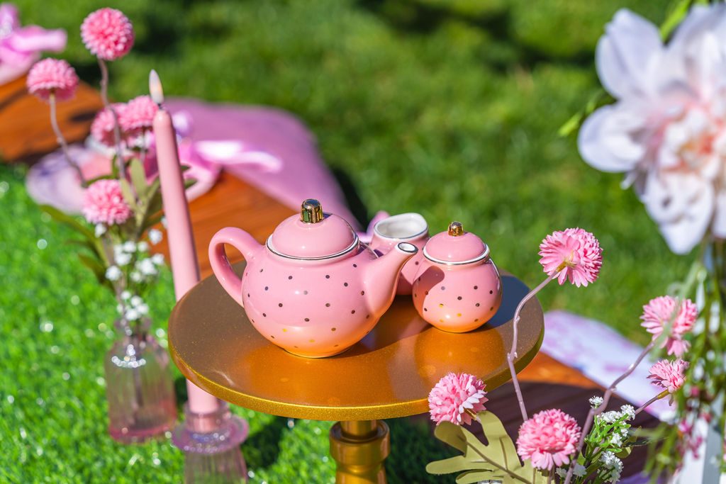 Pink teapots, candles and carnations on the tea table at a princess travel party