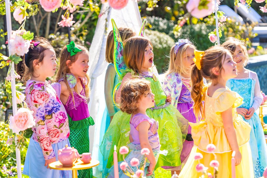 Children in dress-up costumes gathered by the pool at a garden party