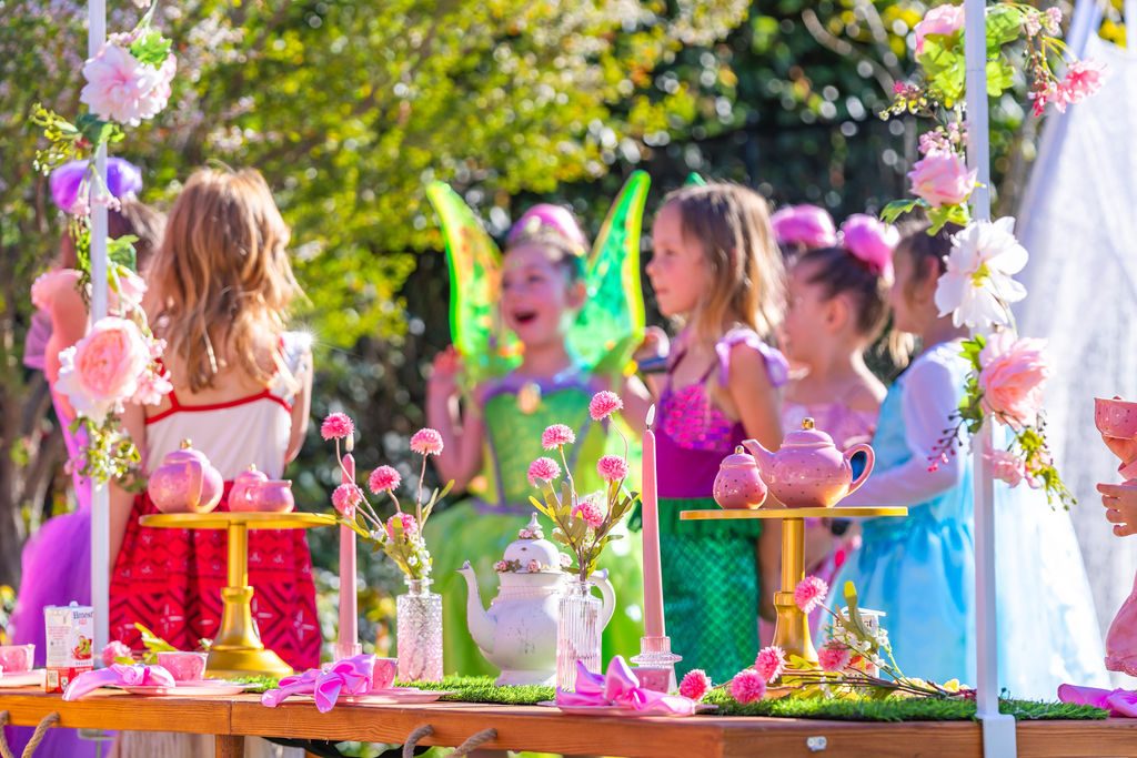 Children in costume seated along the decorated picnic table at a garden travel party