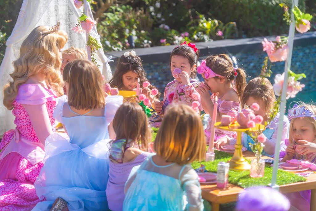 Children seated at the decorated table while the characters serve them