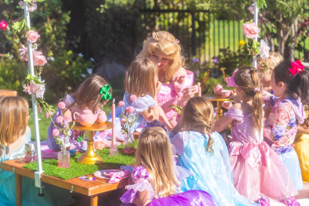 The characters seated along the tea table with the children