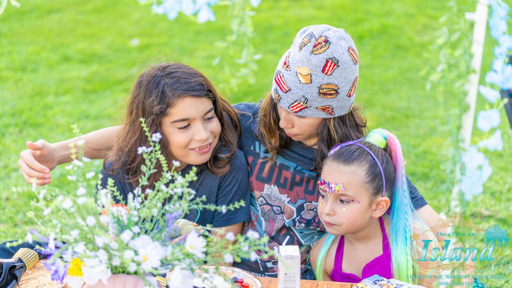 A child having face gems applied at a mermaid travel party
