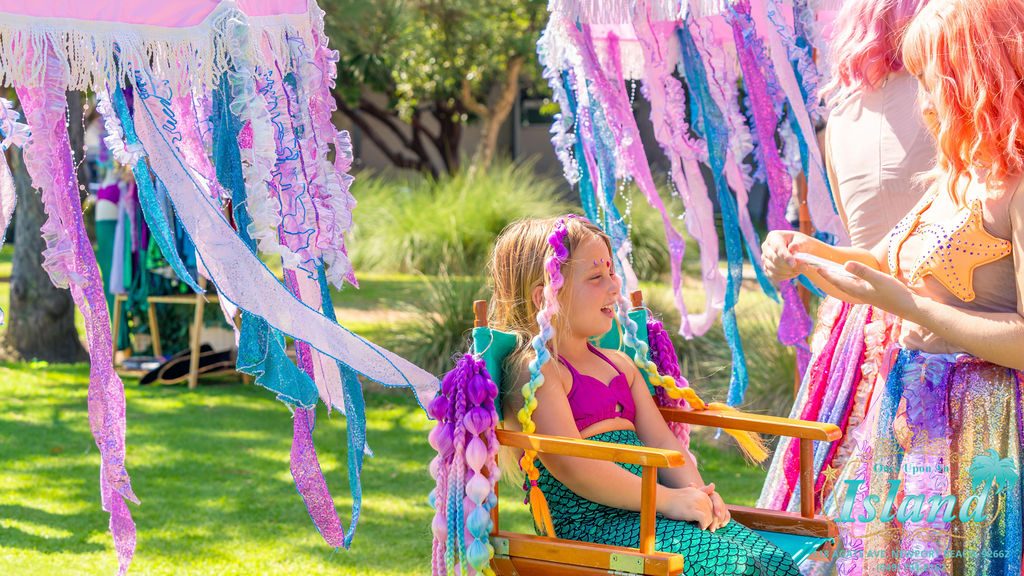 A child in the salon chair having her hair styled at a mermaid travel party