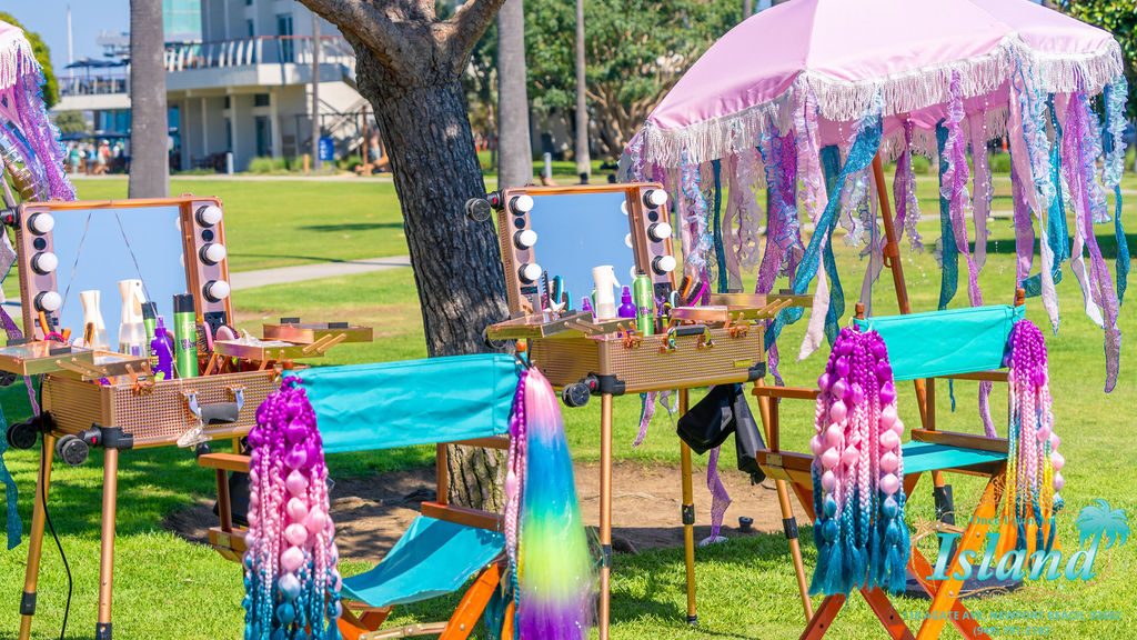 Lit salon stations with mermaid tails set up under fringed umbrellas at a travel party