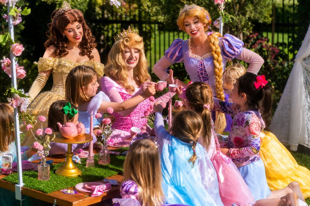 Three princesses pouring tea for children at an Ultimate Princess Tea Party in Orange County