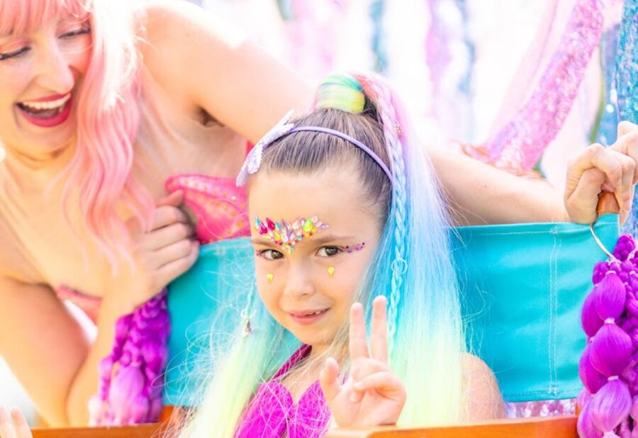 A rainbow mermaid ponytail and face gems from the traveling salon