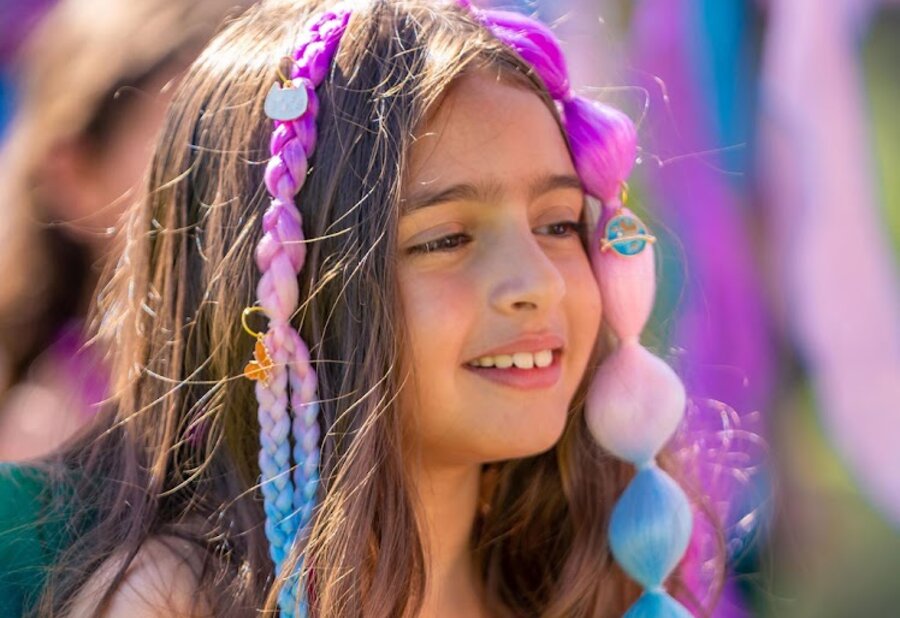 A child showing off her rainbow mermaid braids