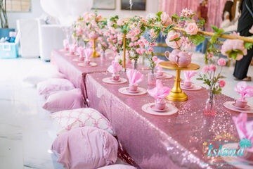 A long pink tablescape with flowers and floor cushions at a spa tea travel party