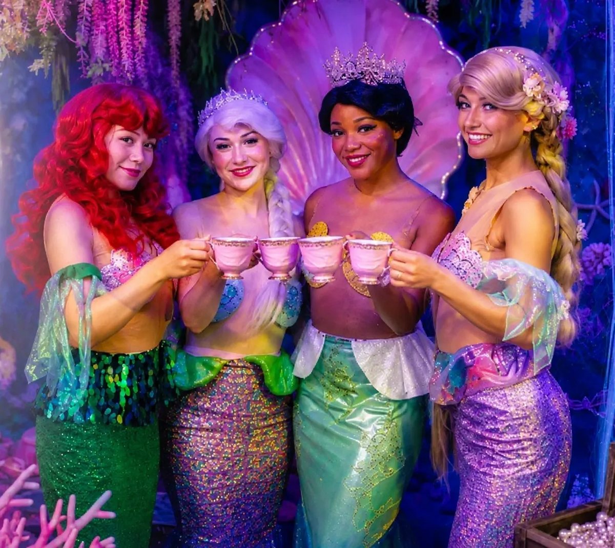 Four princess hosts raising teacups together at an Ultimate Princess Tea Party in Newport Beach