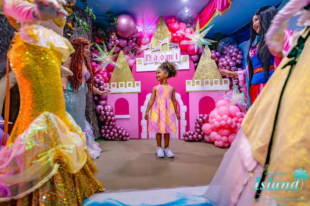 The birthday girl welcomed into a custom pink castle built for her name, framed by her princesses