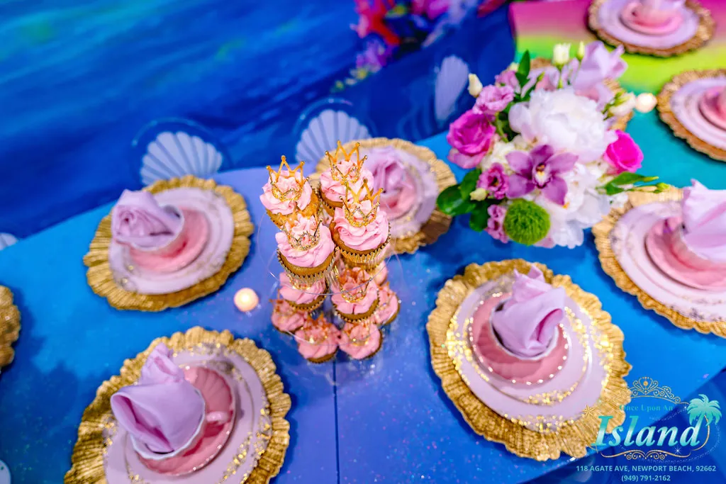 Crowned cupcakes and gold place settings on the shell table