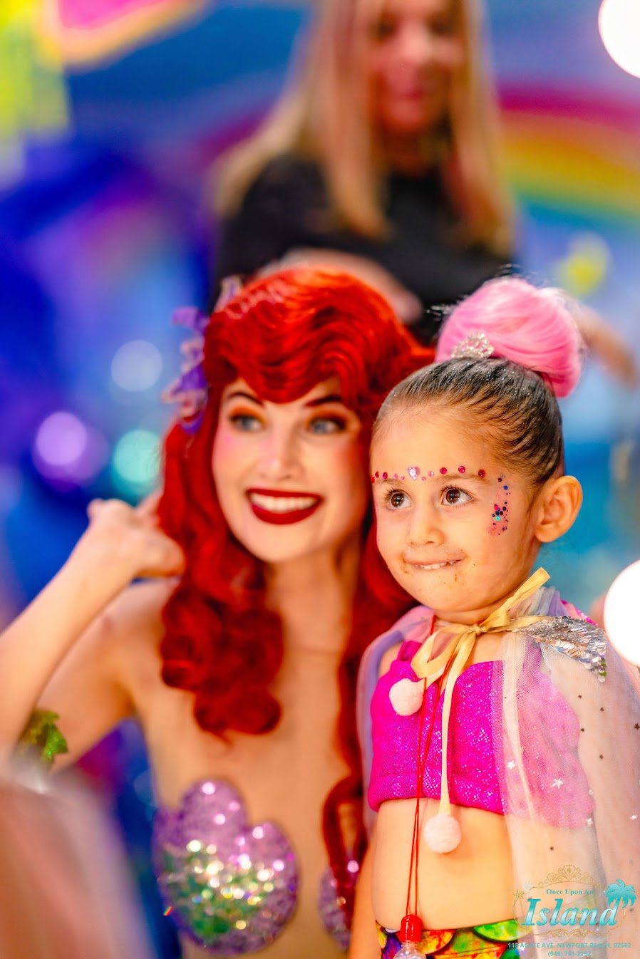 A birthday girl in mermaid face gems posing with the Mermaid Princess