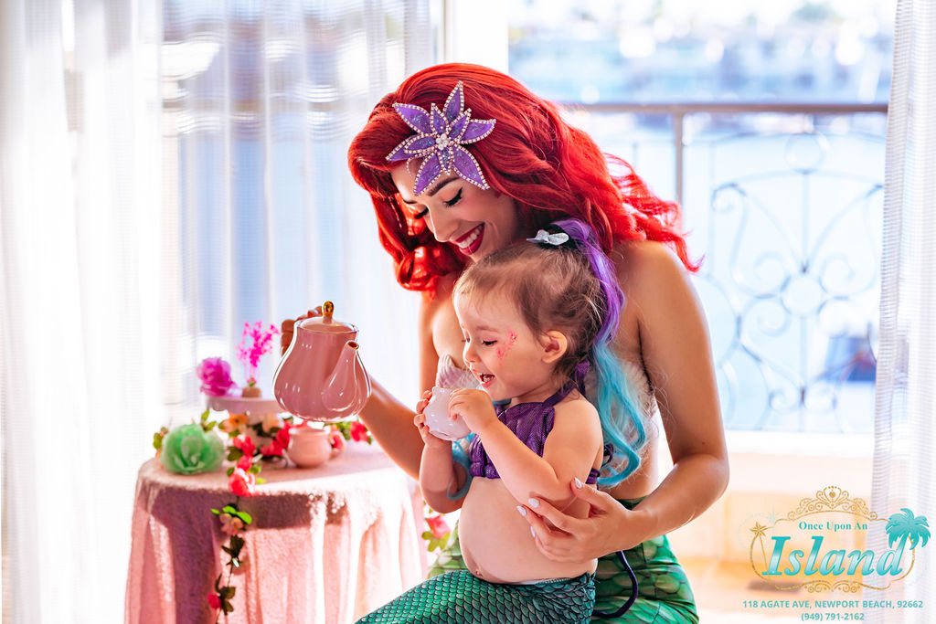 The Mermaid Princess pouring tea for a small guest at a hotel party