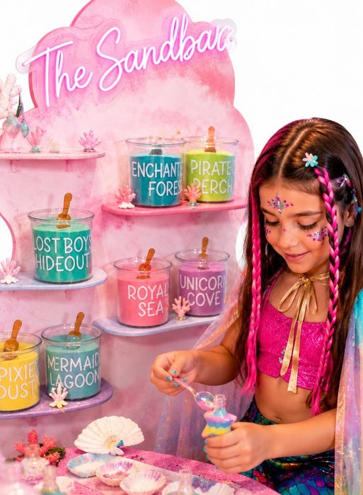A child creating a layered sand keepsake at our Sandbar craft station