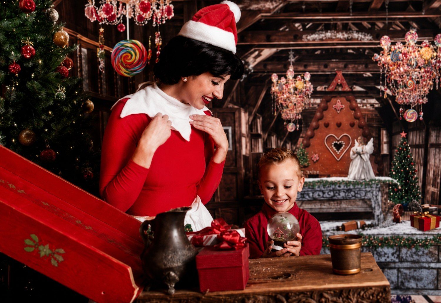 An elf helping a child make a snow globe in Santa&rsquo;s toy factory